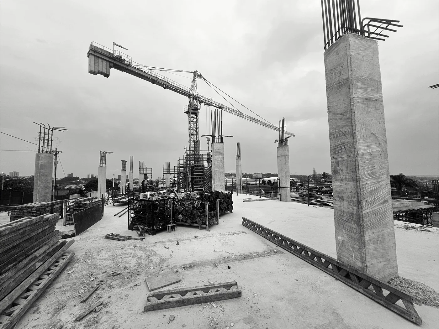 Concrete column and tower cranes above an active construction floor